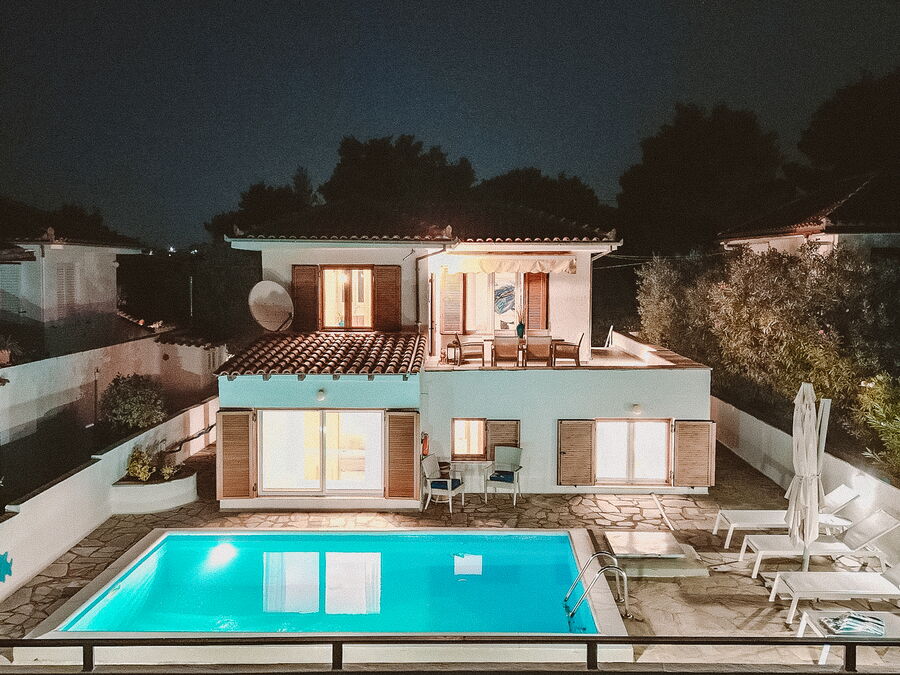 Illuminated villa and pool at night